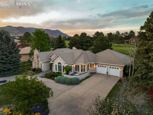 3479 Hill Cir, Colorado Springs, CO 80904 - single story home with a garage, driveway, a mountain view, a tiled roof, and a chimney