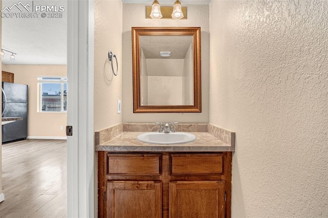 1810 Lanka Ln, Colorado Springs, CO 80915 - bathroom featuring a textured wall, vanity, wood finished floors, and a textured ceiling