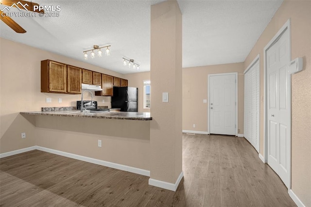 1810 Lanka Ln, Colorado Springs, CO 80915 - kitchen with freestanding refrigerator, wood finished floors, under cabinet range hood, and brown cabinetry