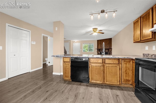 1810 Lanka Ln, Colorado Springs, CO 80915 - kitchen with black appliances, a sink, a peninsula, brown cabinetry, and light wood-style floors