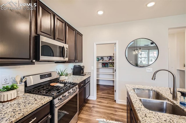 1747 Satin Spar Pt, Colorado Springs, CO 80908 - kitchen with appliances with stainless steel finishes, a sink, dark brown cabinets, light stone counters, and light wood-style flooring