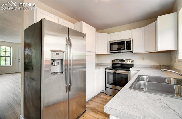 5573 Tamworth Dr, Colorado Springs, CO 80919 - kitchen with appliances with stainless steel finishes, a sink, light wood-style flooring, light countertops, and white cabinetry