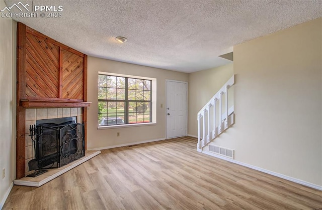 5573 Tamworth Dr, Colorado Springs, CO 80919 - unfurnished living room with stairway, wood finished floors, a textured ceiling, baseboards, and a fireplace