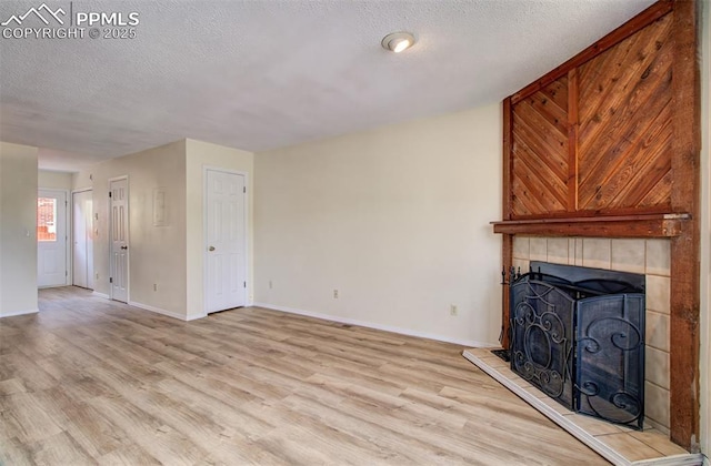 5573 Tamworth Dr, Colorado Springs, CO 80919 - unfurnished living room featuring wood finished floors, a fireplace, a textured ceiling, and baseboards