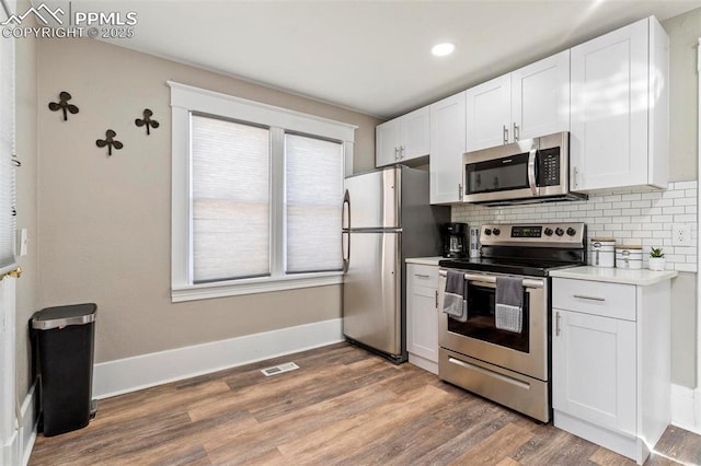 1807 W Colorado Ave, Colorado Springs, CO 80904 - kitchen featuring appliances with stainless steel finishes, light wood finished floors, backsplash, light countertops, and white cabinetry