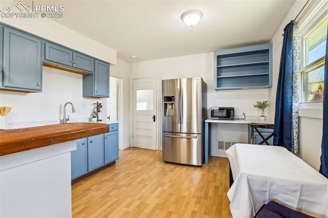 133 W Golden Ave, Cripple Creek, CO 80813 - kitchen with stainless steel fridge, butcher block counters, blue cabinets, and light wood-style floors