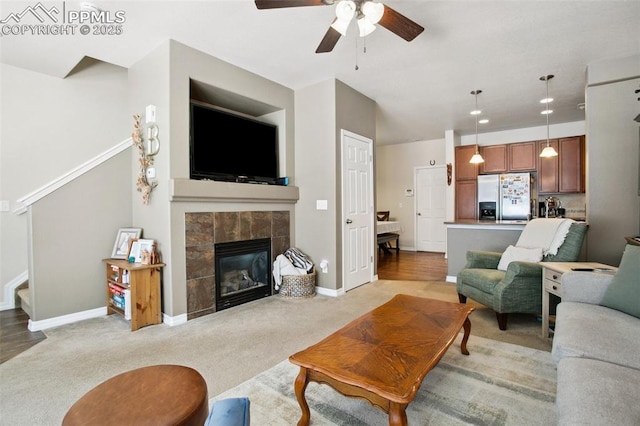 4219 Mesa Point, Colorado Springs, CO 80923 - living room featuring a ceiling fan, stairs, baseboards, a tile fireplace, and light colored carpet