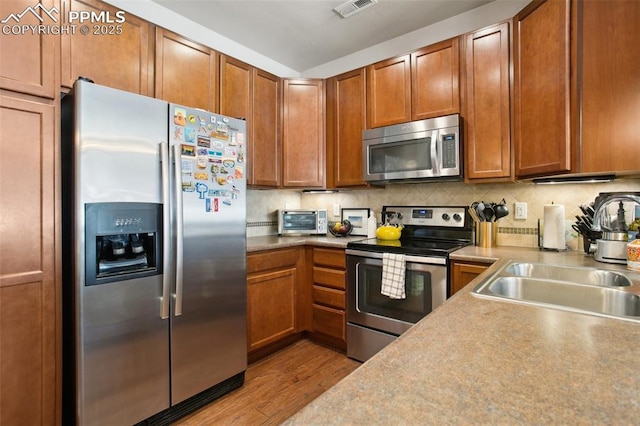 4219 Mesa Point, Colorado Springs, CO 80923 - kitchen featuring appliances with stainless steel finishes, wood finished floors, a sink, and brown cabinetry