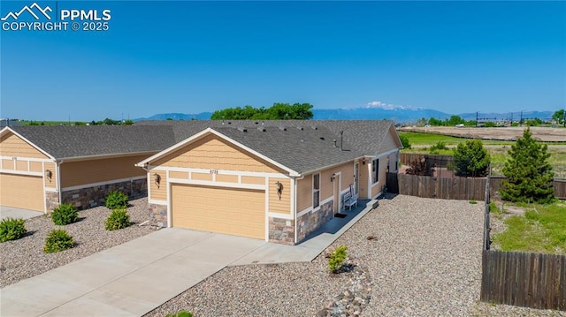 6728 Gelbvieh Rd, Peyton, CO 80831 - view of front of property with stone siding, a mountain view, a garage, driveway, and roof with shingles