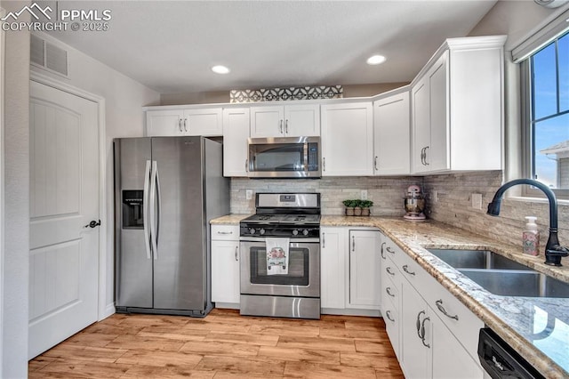 6728 Gelbvieh Rd, Peyton, CO 80831 - kitchen featuring appliances with stainless steel finishes, white cabinets, light wood-style floors, backsplash, and recessed lighting