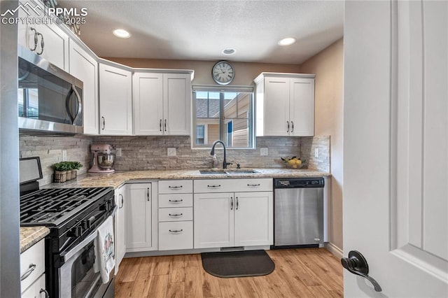 6728 Gelbvieh Rd, Peyton, CO 80831 - kitchen with appliances with stainless steel finishes, tasteful backsplash, white cabinetry, light wood-style floors, and light stone counters