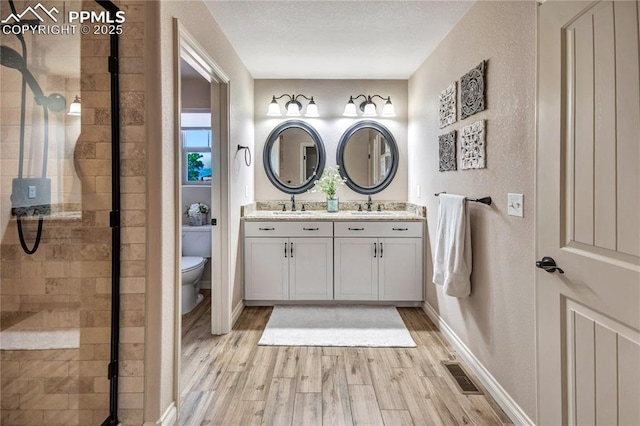 6728 Gelbvieh Rd, Peyton, CO 80831 - bathroom with double vanity, a stall shower, wood finished floors, and a textured wall