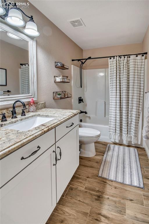 6728 Gelbvieh Rd, Peyton, CO 80831 - bathroom featuring vanity, shower / bath combination with curtain, and wood finished floors