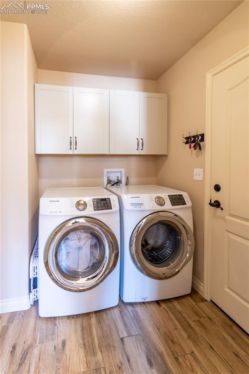 6728 Gelbvieh Rd, Peyton, CO 80831 - washroom with cabinet space, washing machine and dryer, and wood finished floors