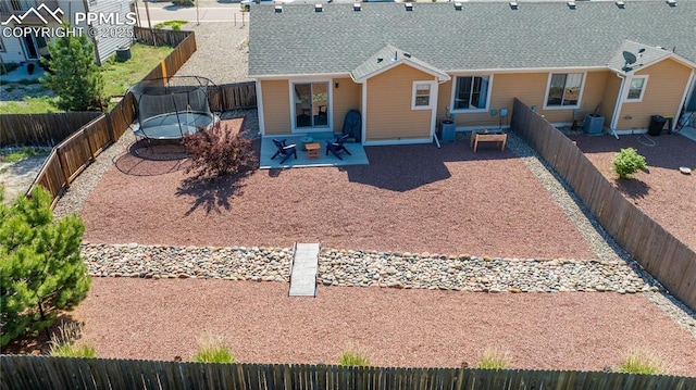 6728 Gelbvieh Rd, Peyton, CO 80831 - rear view of house with a trampoline, a patio area, a fenced backyard, and roof with shingles