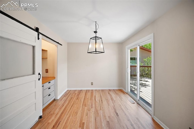 1515 W Boulder St, Colorado Springs, CO 80904 - unfurnished dining area featuring a barn door, light wood-style floors, and baseboards