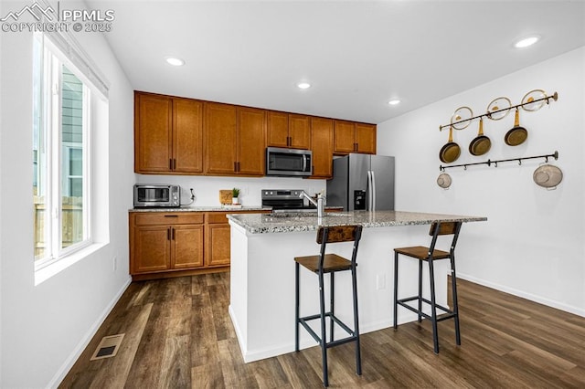10597 Luneth Dr, Colorado Springs, CO 80925 - kitchen with stainless steel appliances, dark wood-style floors, a breakfast bar area, healthy amount of natural light, and recessed lighting