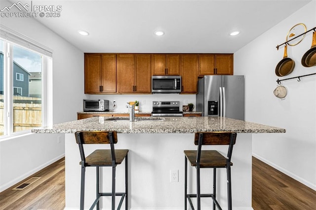 10597 Luneth Dr, Colorado Springs, CO 80925 - kitchen featuring stainless steel appliances, dark wood-type flooring, brown cabinetry, light stone countertops, and recessed lighting