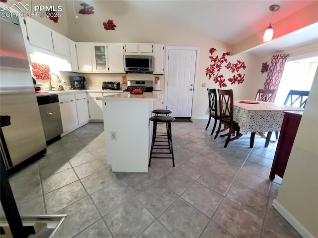 2115 Rangeview Dr, Pueblo, CO 81008 - kitchen featuring stainless steel appliances, vaulted ceiling, a kitchen island, white cabinetry, and light countertops