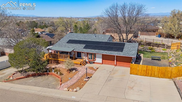 2115 Rangeview Dr, Pueblo, CO 81008 - view of front facade with a shingled roof, roof mounted solar panels, an attached garage, a mountain view, and driveway