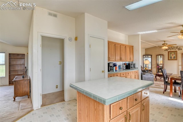 20040 Drennan Rd, Colorado Springs, CO 80928 - kitchen with lofted ceiling, a ceiling fan, stainless steel microwave, a center island, and light carpet