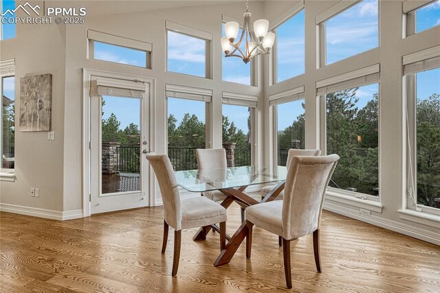 14745 Millhaven Pl, Colorado Springs, CO 80908 - dining space featuring baseboards, wood finished floors, a chandelier, and a high ceiling