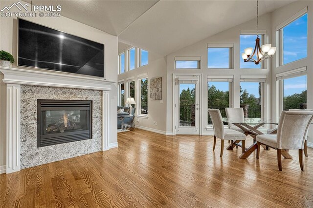 14745 Millhaven Pl, Colorado Springs, CO 80908 - dining space with a chandelier, high vaulted ceiling, wood finished floors, a fireplace, and baseboards