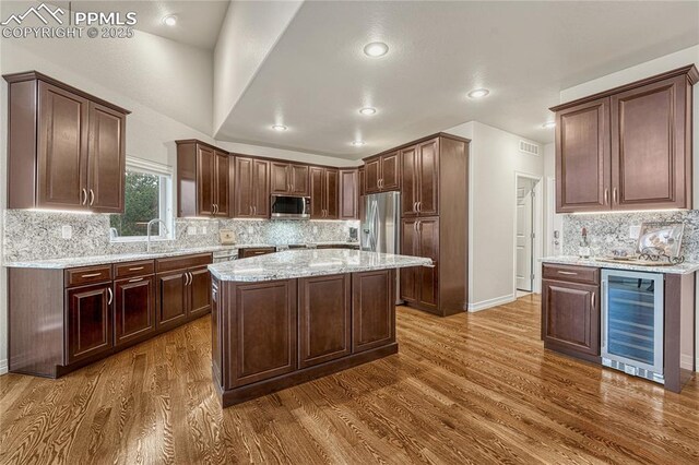 14745 Millhaven Pl, Colorado Springs, CO 80908 - kitchen with beverage cooler, stainless steel appliances, dark wood-type flooring, backsplash, and light stone counters