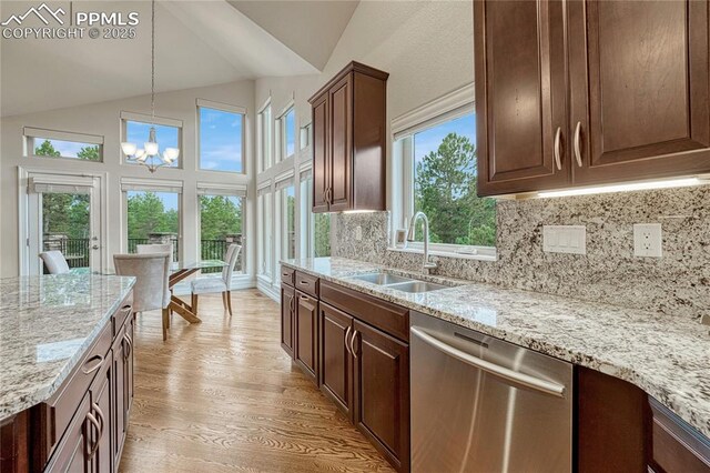 14745 Millhaven Pl, Colorado Springs, CO 80908 - kitchen with stainless steel dishwasher, a sink, vaulted ceiling, a chandelier, and light wood-style floors