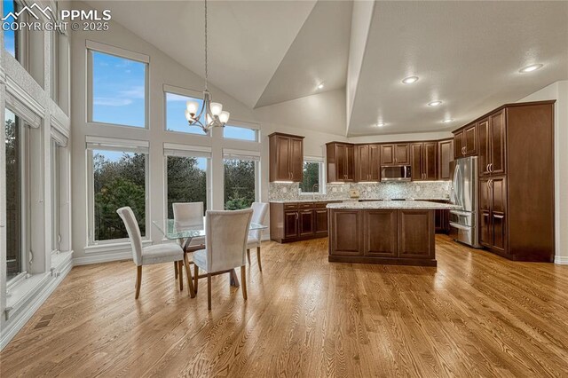 14745 Millhaven Pl, Colorado Springs, CO 80908 - kitchen featuring stainless steel appliances, vaulted ceiling, a chandelier, tasteful backsplash, and light wood finished floors