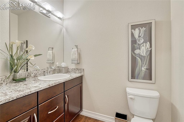 14745 Millhaven Pl, Colorado Springs, CO 80908 - bathroom featuring vanity, toilet, wood finished floors, and baseboards