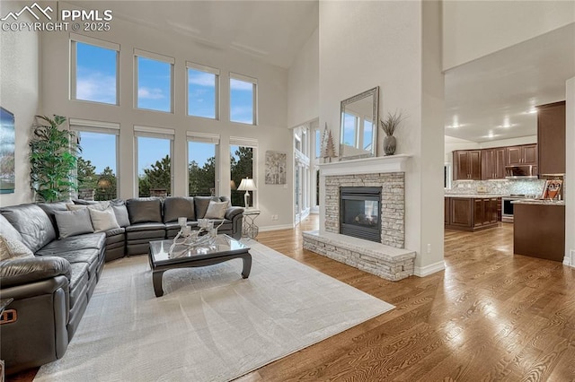 14745 Millhaven Pl, Colorado Springs, CO 80908 - living room with a towering ceiling, light wood finished floors, a fireplace, and baseboards