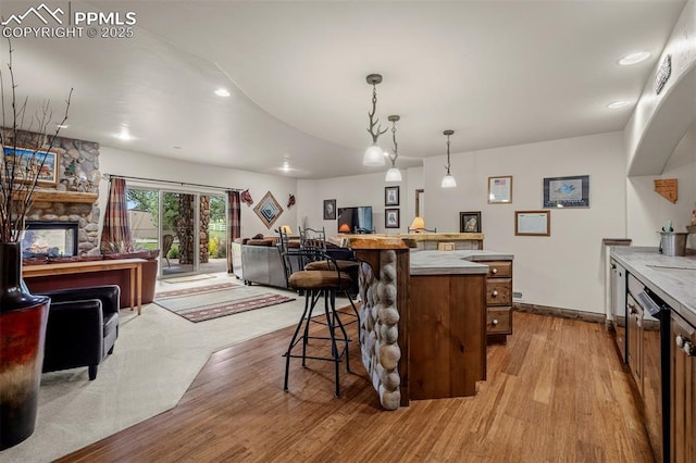 8610 Wildridge Rd, Colorado Springs, CO 80908 - kitchen featuring a kitchen bar, open floor plan, wood finished floors, a stone fireplace, and dishwashing machine