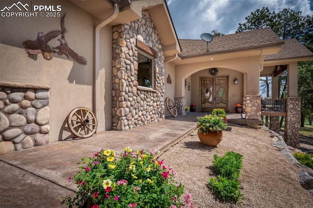 8610 Wildridge Rd, Colorado Springs, CO 80908 - property entrance with stone siding, stucco siding, french doors, a shingled roof, and a porch