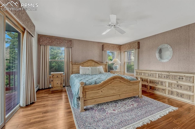 17580 Chipped Arrow Way, Monument, CO 80132 - bedroom with wallpapered walls, access to exterior, light wood finished floors, ceiling fan, and a baseboard heating unit