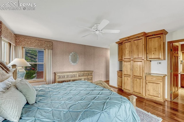 17580 Chipped Arrow Way, Monument, CO 80132 - bedroom with light wood finished floors, wallpapered walls, and ceiling fan