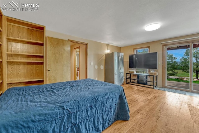 17580 Chipped Arrow Way, Monument, CO 80132 - bedroom with freestanding refrigerator, access to exterior, multiple windows, and wood finished floors