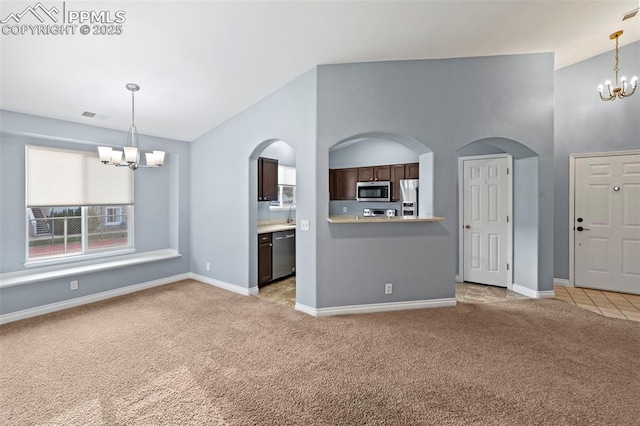 3730 Penny Pt Unit G, Colorado Springs, CO 80906 - unfurnished living room with a chandelier, light carpet, arched walkways, baseboards, and vaulted ceiling