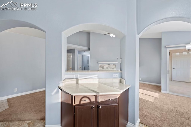 3730 Penny Pt Unit G, Colorado Springs, CO 80906 - kitchen with light carpet, dark brown cabinets, arched walkways, and baseboards