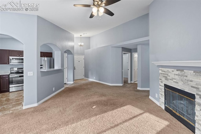 3730 Penny Pt Unit G, Colorado Springs, CO 80906 - unfurnished living room featuring light colored carpet, a ceiling fan, a stone fireplace, baseboards, and a high ceiling