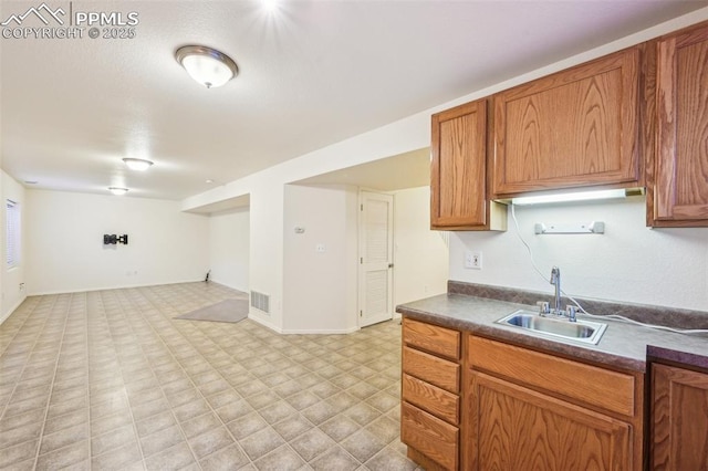 7619 Steward Ln, Colorado Springs, CO 80922 - kitchen featuring a sink, dark countertops, light floors, brown cabinetry, and open floor plan