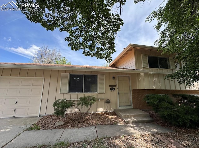 1402 Yosemite Dr, Colorado Springs, CO 80910 - view of front of house with board and batten siding, an attached garage, concrete driveway, and brick siding