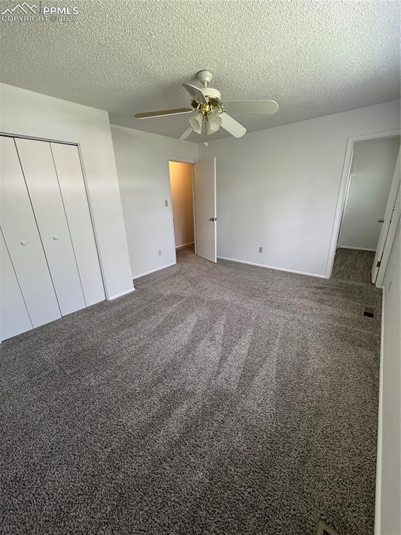 1402 Yosemite Dr, Colorado Springs, CO 80910 - unfurnished bedroom with a textured ceiling, carpet floors, a closet, a ceiling fan, and baseboards