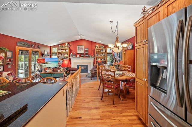 435 W Woodmen Rd, Colorado Springs, CO 80919 - kitchen with stainless steel refrigerator with ice dispenser, light wood-type flooring, lofted ceiling, a chandelier, and a lit fireplace