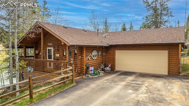 1369 Spring Valley Dr, Divide, CO 80814 - log-style house featuring driveway, a shingled roof, an attached garage, and log siding