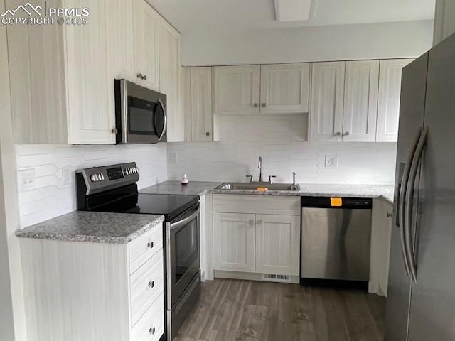 10910 Double D Rd, Fountain, CO 80817 - kitchen featuring stainless steel appliances, a sink, decorative backsplash, and dark wood finished floors