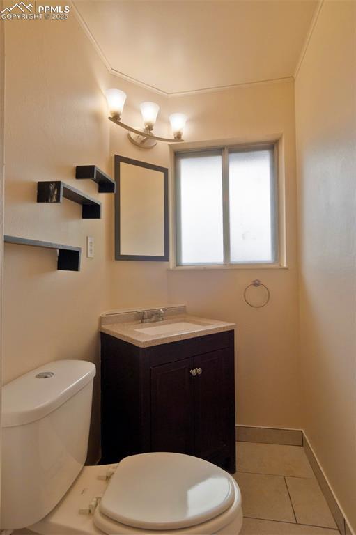1934 Berkshire Ln, Colorado Springs, CO 80909 - half bathroom with toilet, vanity, baseboards, and tile patterned floors
