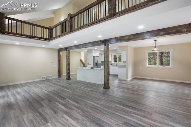 595 Wintery Cir, Colorado Springs, CO 80919 - unfurnished living room featuring a barn door, a towering ceiling, dark wood-style flooring, baseboards, and recessed lighting