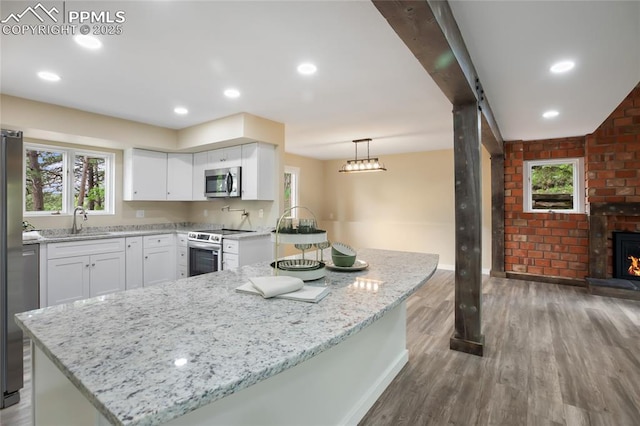 595 Wintery Cir, Colorado Springs, CO 80919 - kitchen featuring appliances with stainless steel finishes, a sink, wood finished floors, light stone counters, and white cabinets