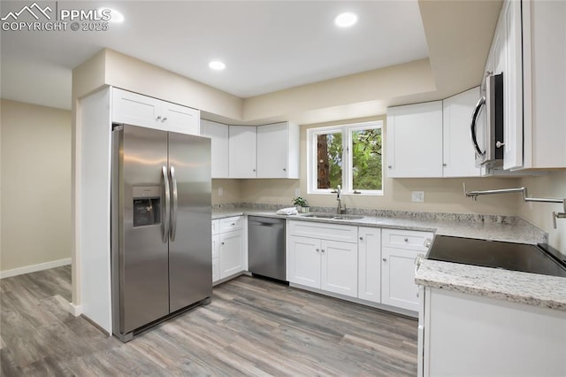 595 Wintery Cir, Colorado Springs, CO 80919 - kitchen with appliances with stainless steel finishes, a sink, light wood finished floors, white cabinetry, and recessed lighting